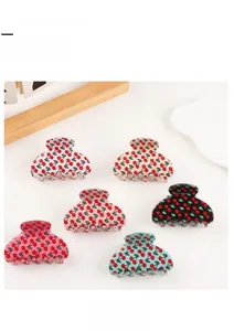 Detailed flat lay of six colorful hair claw clips with cherry patterns on a ceramic plate