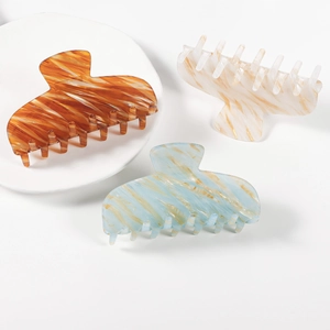 Three elegant marble texture claw clips in amber, cream, and light blue finishes