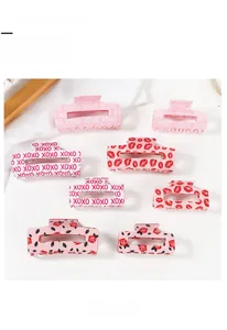 Detail view of 8 pink Valentine hair claws with rose, lip prints, and XOXO patterns