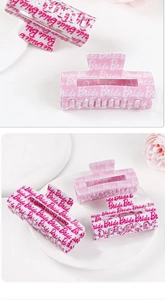 Close-up of pink and white acetate hair claws with Bride text for wedding accessories