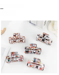 Detail showing five different cartoon animal print hair claw clips in a minimalist setting