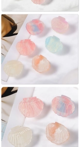 Macro detail of shell-shaped hair claws with pearlescent marble texture in pastel colors