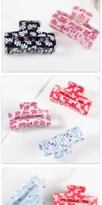 Detailed macro view showing diverse floral and heart patterns on acrylic hair claw clips