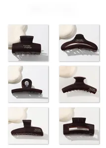 Detail view of six dark brown hair claws with elegant golden French lettering
