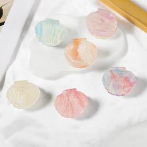 Elegant shell-shaped hair claws in macaron marble colors set on a white ceramic tray