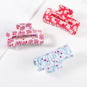 Three colorful floral hair claws in pink and blue with heart patterns on white background