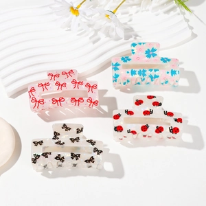 Set of four pastel acetate hair claws with bow and floral patterns on white stand