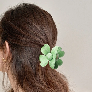 Green plaid four-petal flower hair claw clip shown on woman's hair in back view