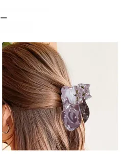 Detailed close-up of a marbled acetate cat hair claw clip worn on a low ponytail