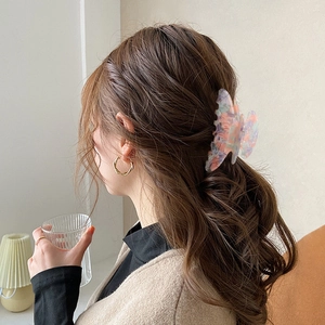 Elegant butterfly hair claw with purple and orange patterns on a model's ponytail