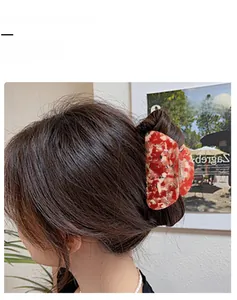 Dettaglio di un grande fermaglio per capelli con motivo floreale arancione marmorizzato