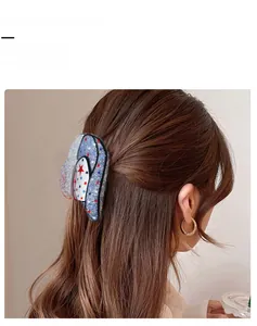 Detail view of blue star patterned hair claw clip on half-up hairstyle with sequins