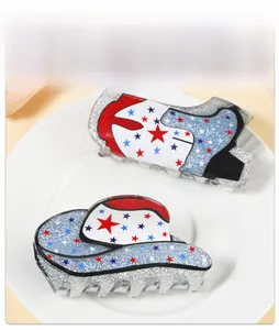 Close-up of glittery acrylic cowboy hat and boot hair claws with colorful star patterns