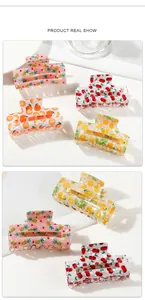 Detailed view of acetate fruit print hair claws featuring cherry and pineapple designs