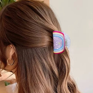 Pince à cheveux lavande chic avec rayures colorées sur cheveux bruns bouclés