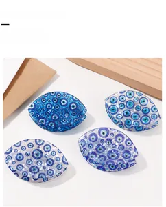 Detail view of blue evil eye hair claw clips on white background with wooden decor