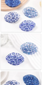 Close-up of blue Evil Eye acetate hair claw clip with glossy finish on wooden tray