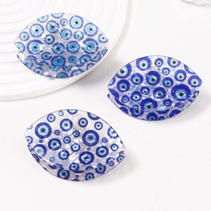 Three blue Evil Eye claw hair clips made of glossy acetate on a white display stand