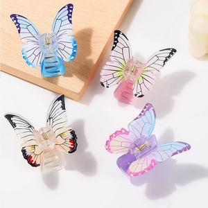 Elegant butterfly hair claw clips in four gradient colors on a wooden display