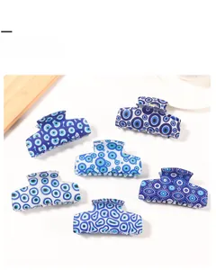 Detailed view of six evil eye patterns on blue and white acrylic hair claw clips set