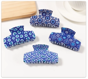 Set of four blue evil eye hair claw clips displayed on a minimal wooden tray