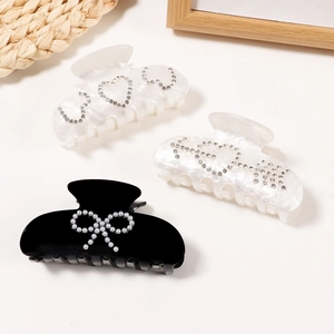 Elegant hair claw clips set with rhinestone hearts and pearl bow designs on beige background