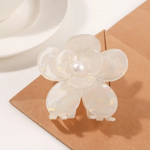 Elegant pearlescent resin flower hair claw with pearl center on brown paper base