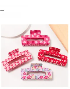 Detail view of four large square hair claw clips with various red and pink heart patterns