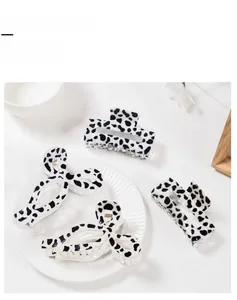 Detail showing cow print resin hair claw clips in various shapes on a white plate