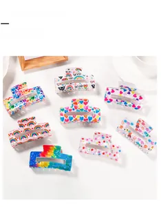Flat lay of colorful rainbow pattern PVC hair claw clips with heart and star designs