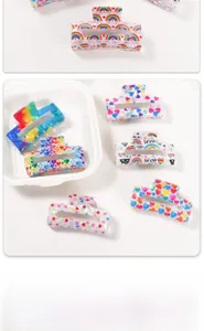 Close-up of rainbow acrylic hair claws with LOVE IS LOVE and PRIDE printed designs