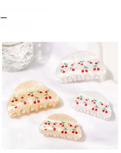 Detailed set of cherry print hair claw clips in cream and pearl white with glossy finish