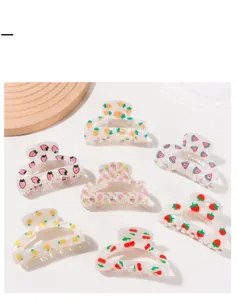 Flat lay of acetate hair claw clips in various fruit designs on a white and wood surface