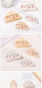 Detail view of cherry pattern hair claws in pearl white and cream yellow finish