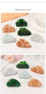 Detail view of leaf shaped hair claws with gold leaf veins in green, amber and blue