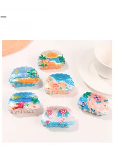 Detail view of shell-shaped hair claws with summer beach patterns on a clean white surface