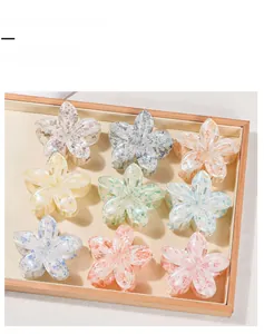 Detail view of nine colorful acetate flower hair claw clips arranged on a wooden tray