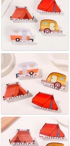 Detailed view of camping-themed hair claws in tent and caravan shapes made of acetate