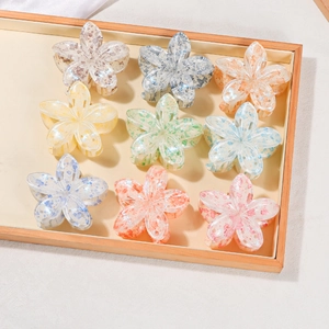 Set of nine translucent acrylic floral hair claws with colorful glitter in a wooden tray