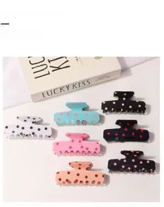Close-up of assorted polka dot hair claw clips in six colors on a white background