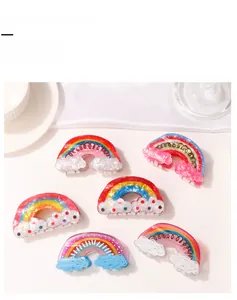 Detail showing various pastel rainbow and cloud hair claw clips on white silk background
