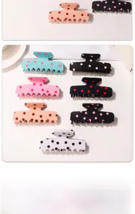 Variety of retro polka dot hair claws in multiple colors arranged on a white ceramic plate