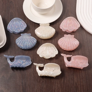 Cute whale and seashell hair claws with iridescent finish and rhinestones on wood