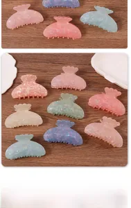 Macro detail of shell-edged hair claws in matte macaron colors with glitter finish