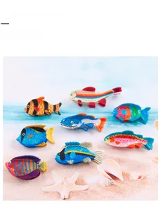 Lot de huit pinces à cheveux en forme de poisson colorées posées sur un décor de plage