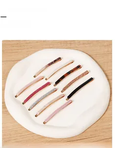Detailed set of ten stylish hair clips with various patterns on a round white display tray