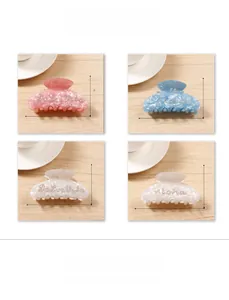 Close-up of marble texture acetate hair claws with rhinestone letters set in four colors