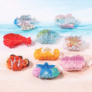 Collection de pinces à cheveux colorées en acétate avec motifs marins sur le sable