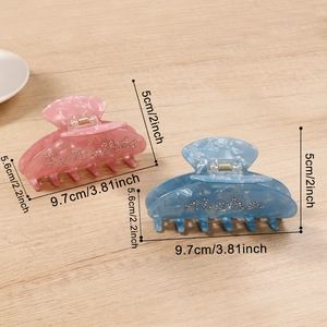 Pink and blue marble hair claws with rhinestone Aloha letters on light wood background