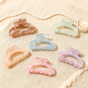 Set of six colorful marble-textured hair claws on beige linen with lifestyle decor